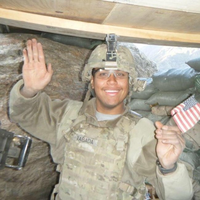 Brian Tabada waving while holding a miniature American flag in his other hand.